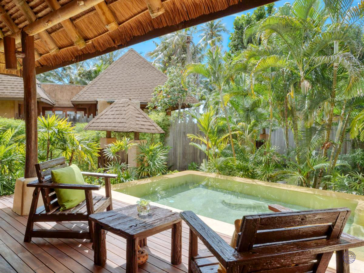 Inviting private pool villa with wooden deck, chairs, and lush tropical garden in Koh Kood.