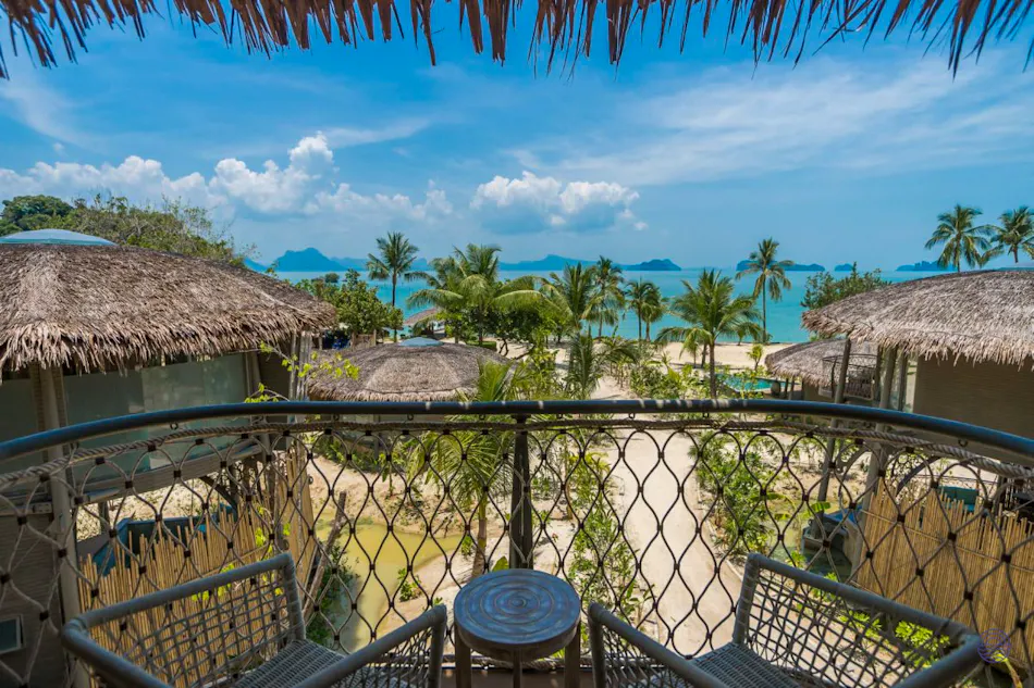 Balcony view from a treehouse villa at Koh Yao Noi, overlooking a tropical beach and turquoise ocean.