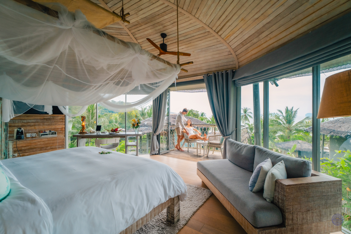 Luxurious bedroom with a person receiving a massage on a balcony at a tropical resort.
