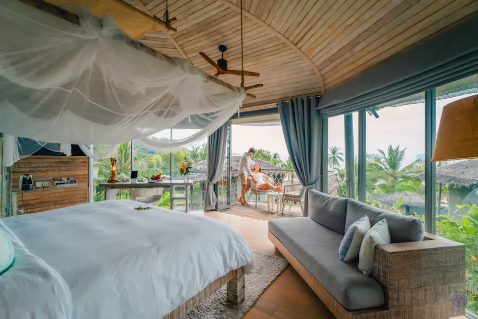 Luxurious bedroom with a person receiving a massage on a balcony at a tropical resort.