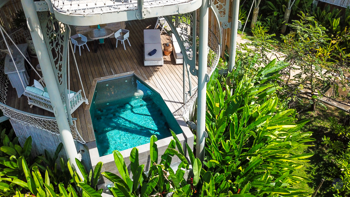 Luxurious treehouse villa with a private plunge pool and deck, nestled within lush tropical foliage.