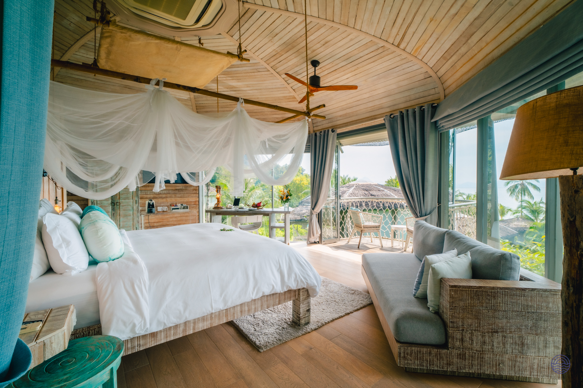 Luxurious bedroom in a Koh Yao Noi treehouse villa, with a large bed and ocean view balcony.