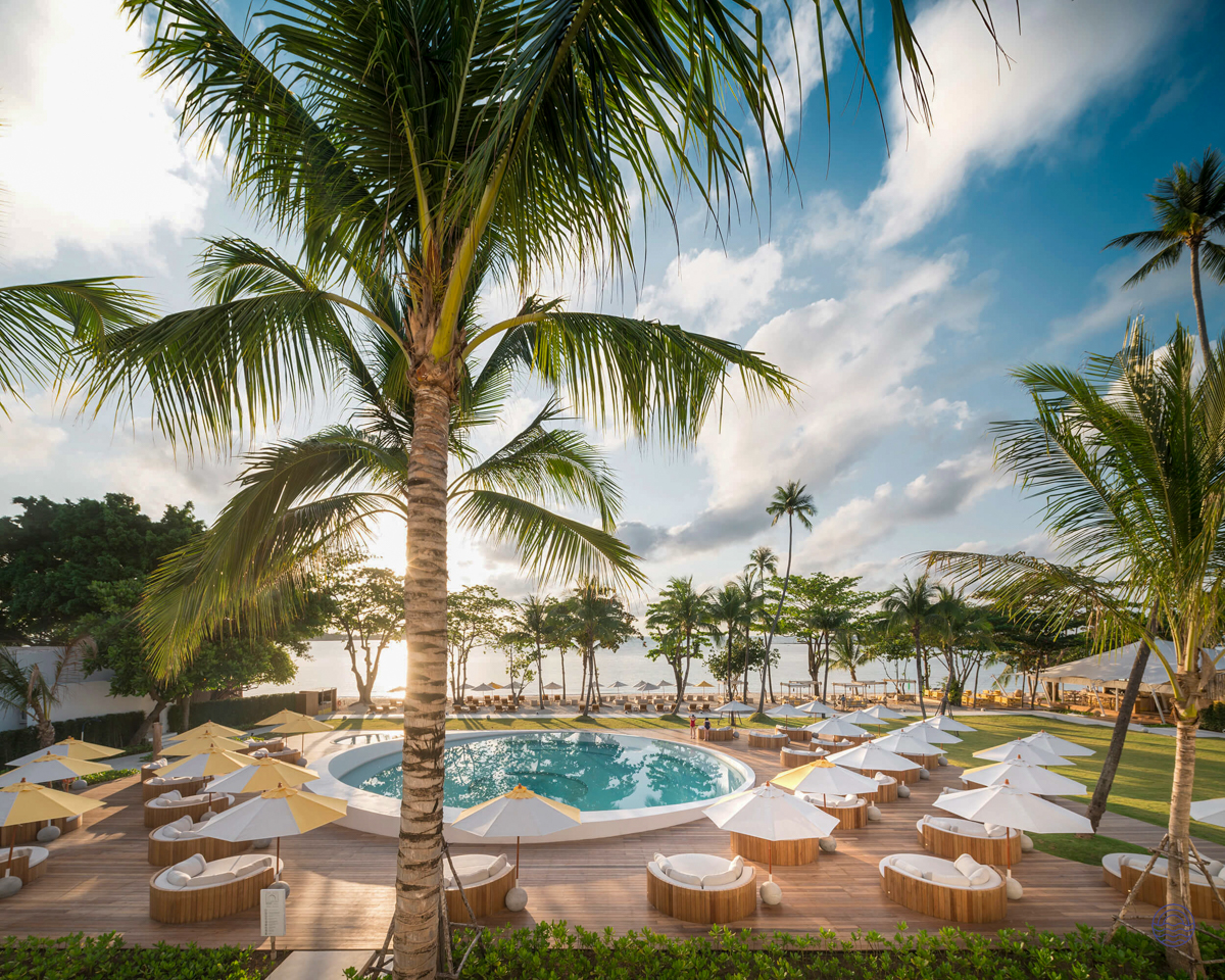 Stunning resort pool and beach with numerous sun loungers and palm trees on Koh Samui.