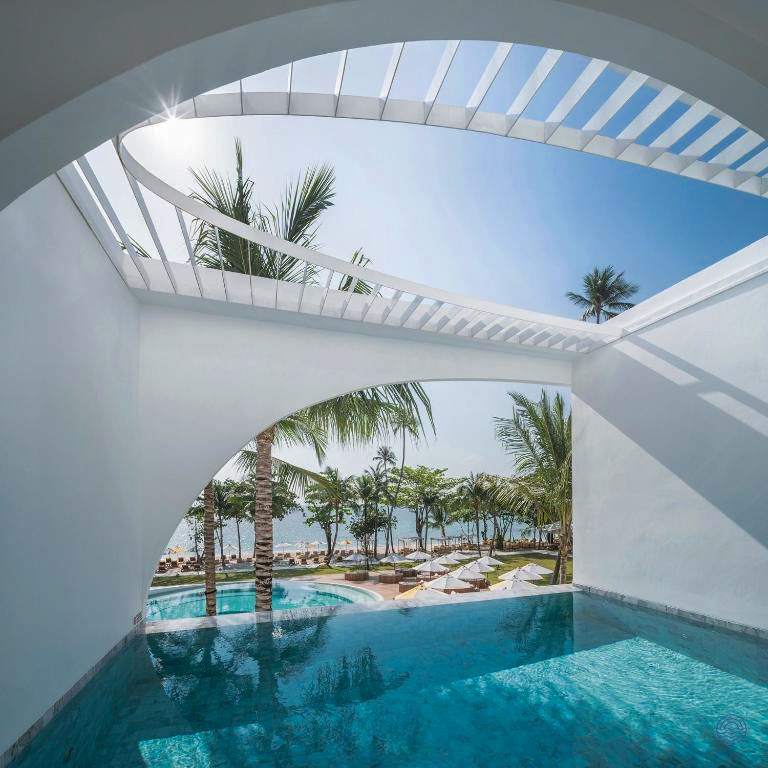 Modern resort architecture frames a private pool, tropical beach, and sparkling ocean in Koh Samui.