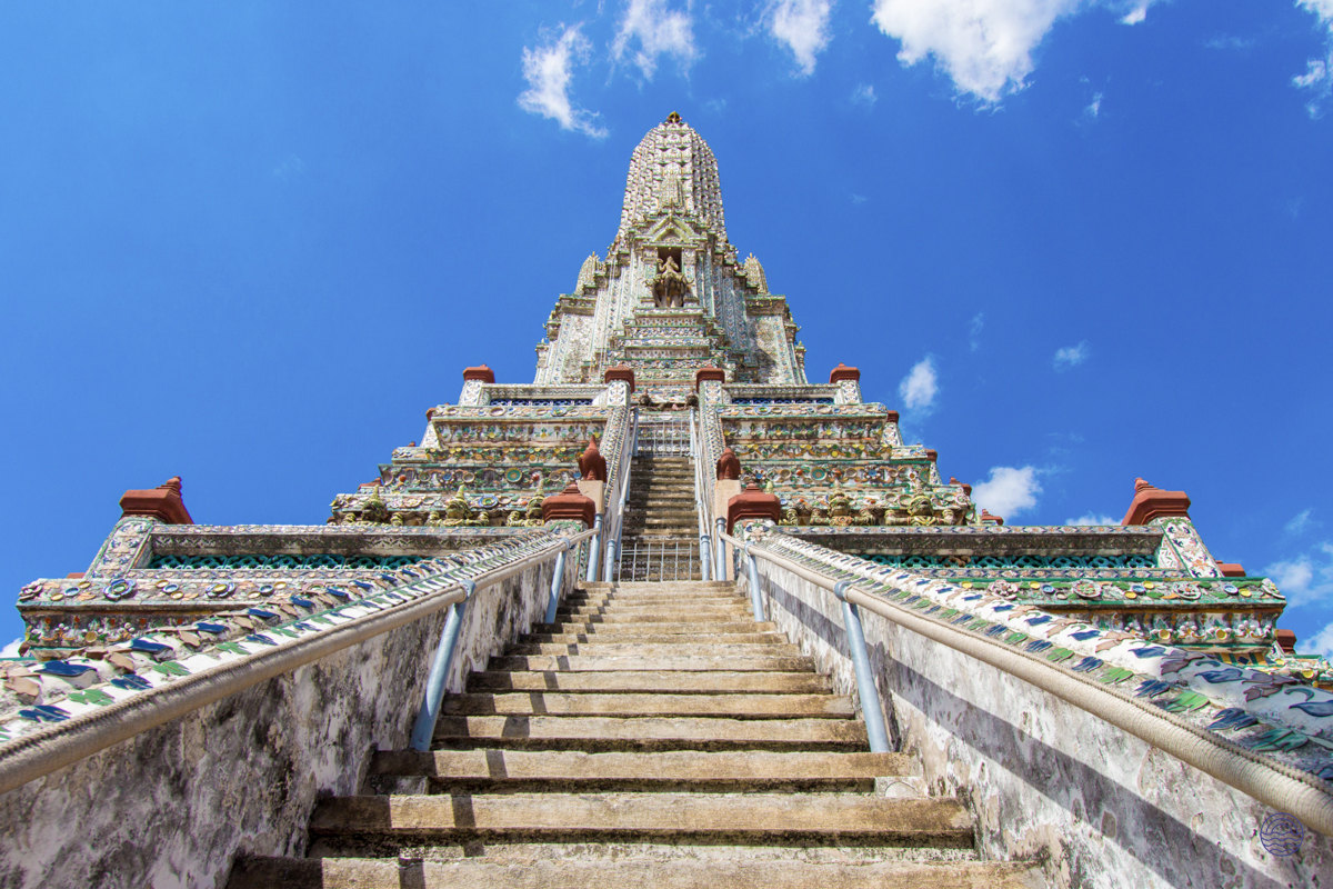 The majestic central prang of Wat Arun temple in Bangkok, showcasing intricate details and steep steps.