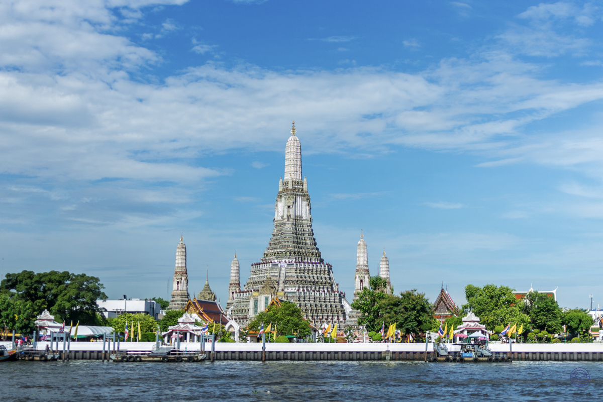 The majestic Wat Arun temple in Bangkok, with its intricate spires, stands by the Chao Phraya River.
