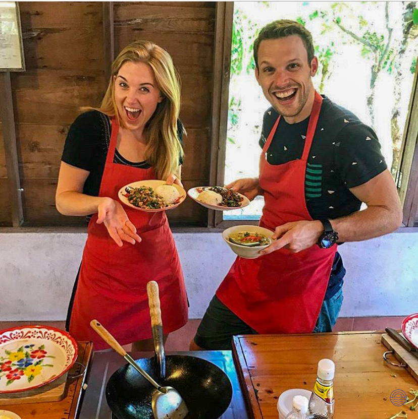 A happy couple proudly displays their freshly cooked Thai dishes during a cooking class in Chiang Mai.