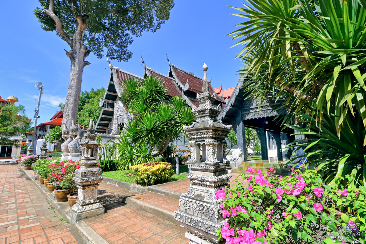 Serene temple grounds in Chiang Mai, featuring traditional architecture, lush gardens, and decorative stone pillars.