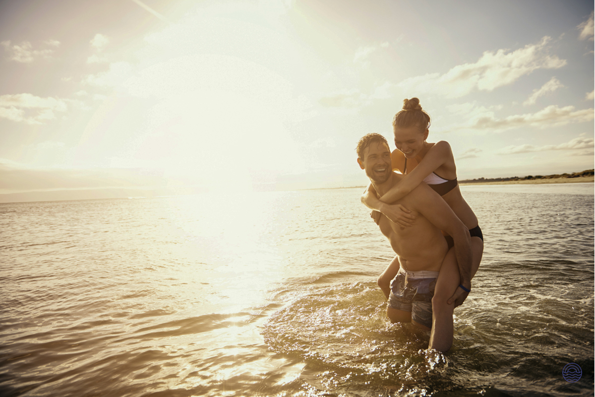 A happy couple enjoying a piggyback ride in the shallow, sunlit waters of Koh Phi Phi.