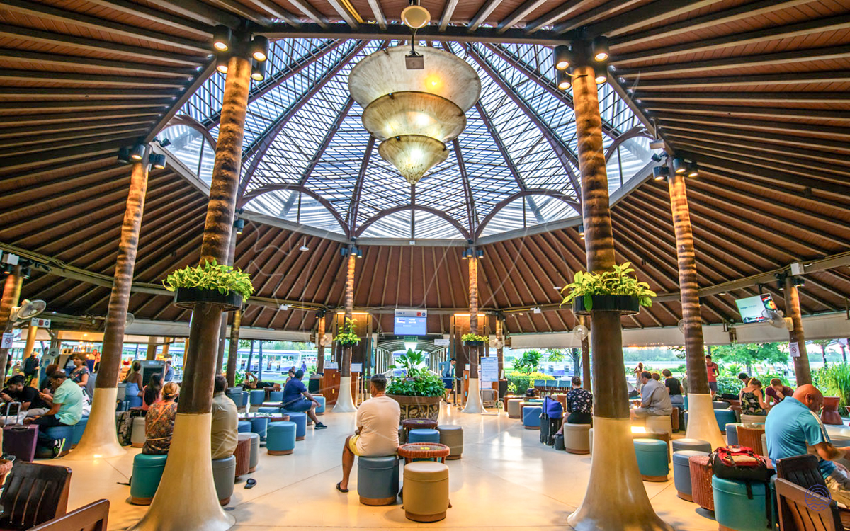 Guests relax in the unique, open-air terminal of Koh Samui Airport under its impressive domed roof.