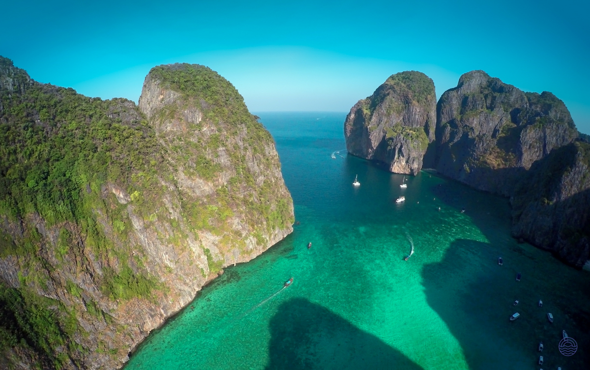 Breathtaking aerial view of crystal-clear turquoise waters and towering limestone cliffs with boats, Koh Phi Phi.