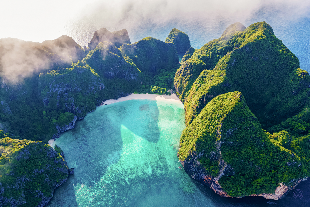Breathtaking aerial view of Koh Phi Phi's secluded beach with lush green limestone cliffs and clear turquoise waters.