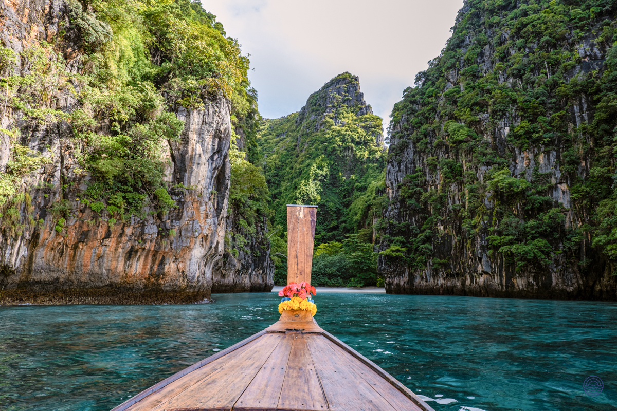 Exploring the stunning emerald waters of Koh Phi Phi by traditional longtail boat, surrounded by lush cliffs.