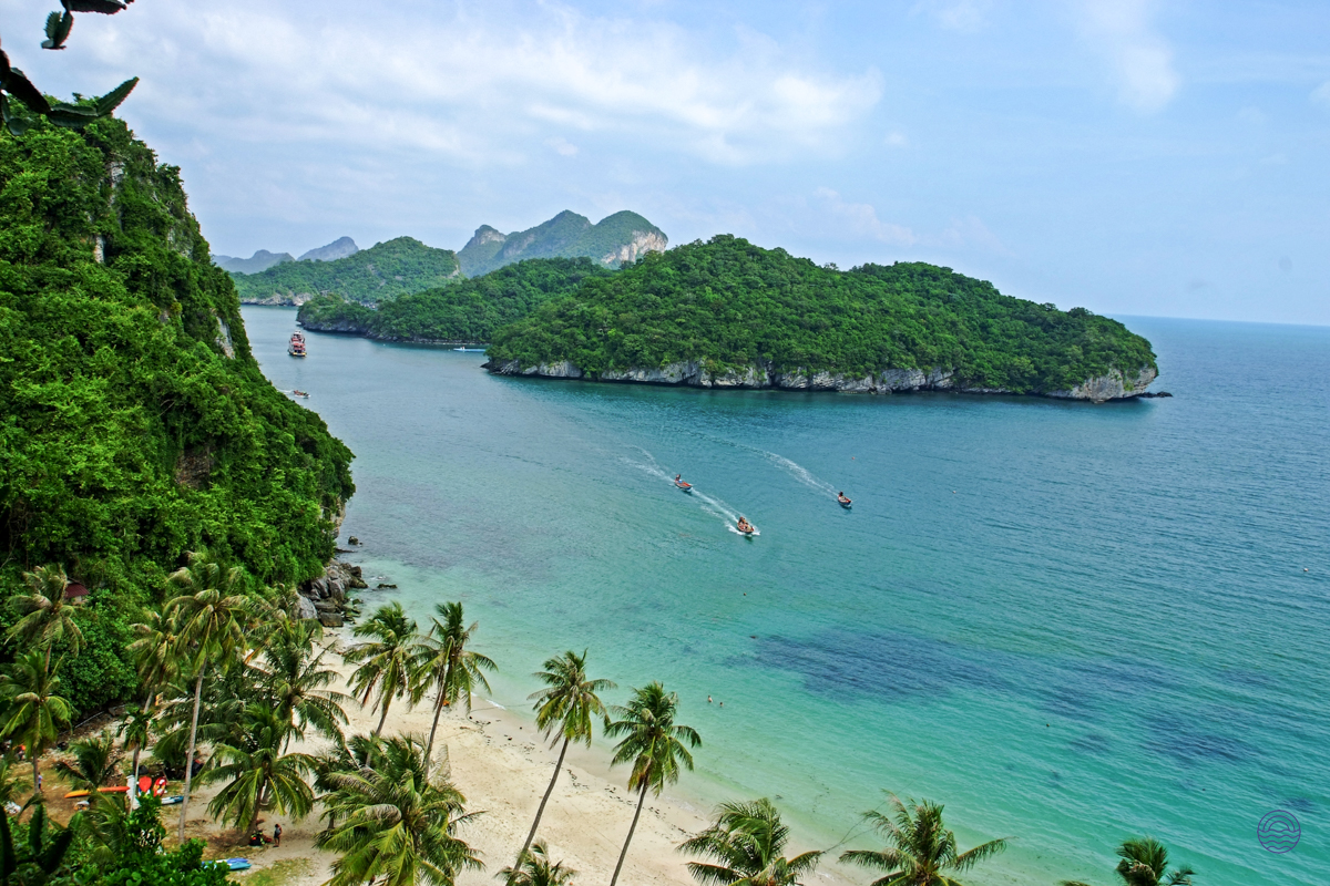 Beautiful Koh Samui bay with lush islands, a sandy beach, and boats on clear turquoise water.