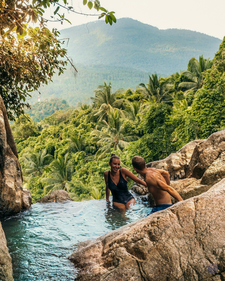 A happy couple enjoys a refreshing swim in a natural waterfall pool on Koh Samui.
