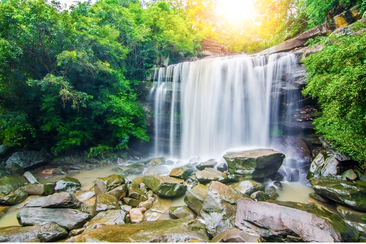 A beautiful waterfall cascades over rocks into a pool surrounded by lush green trees on Koh Samui.