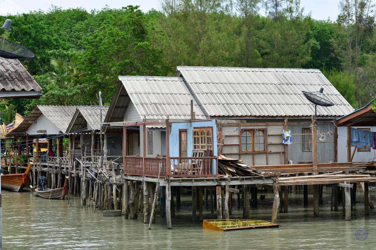 Traditional wooden houses on stilts over calm water in a charming fishing village on Koh Yao Noi.