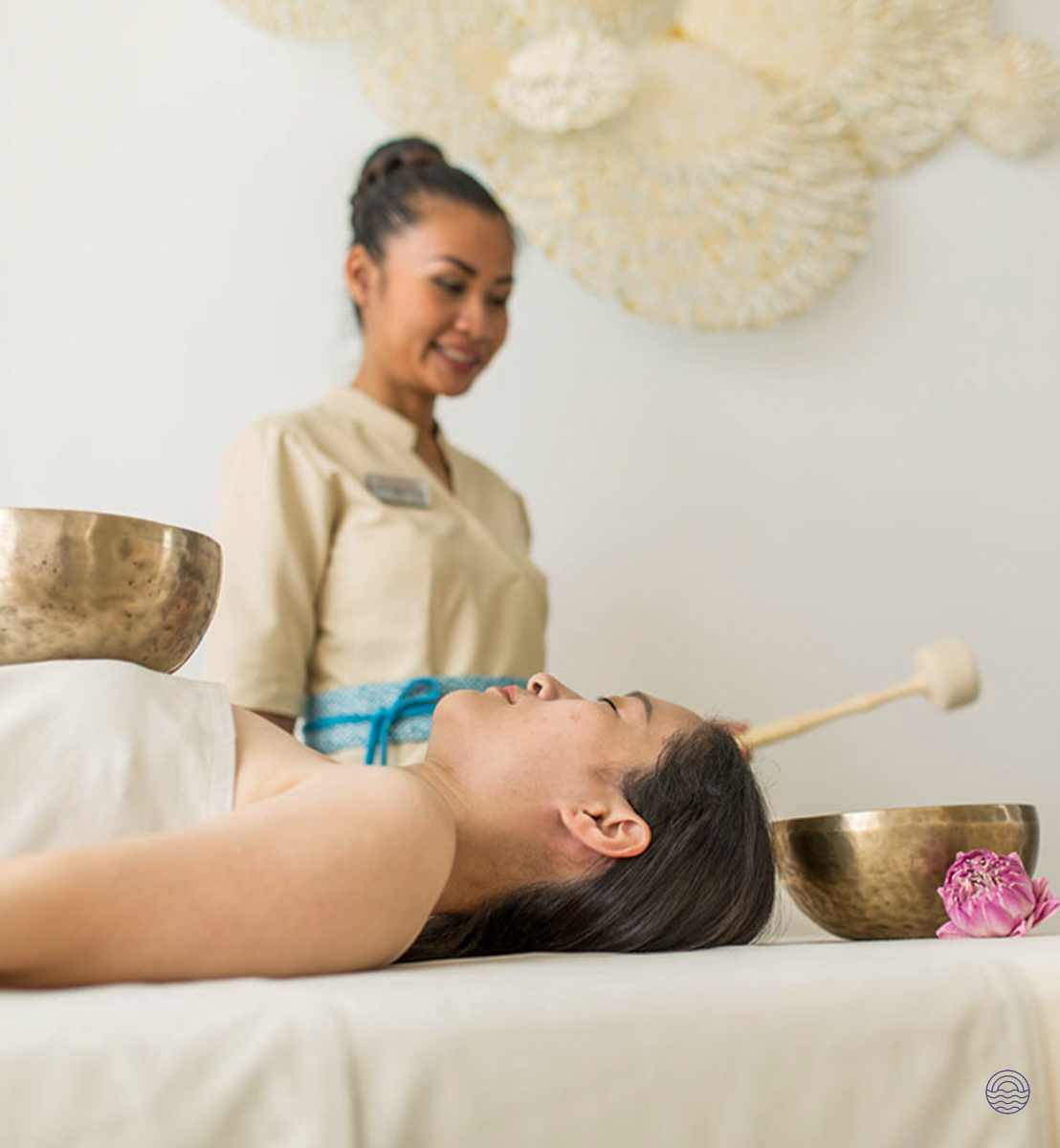 A woman relaxes during a luxurious singing bowl spa treatment in Phuket, attended by a therapist.