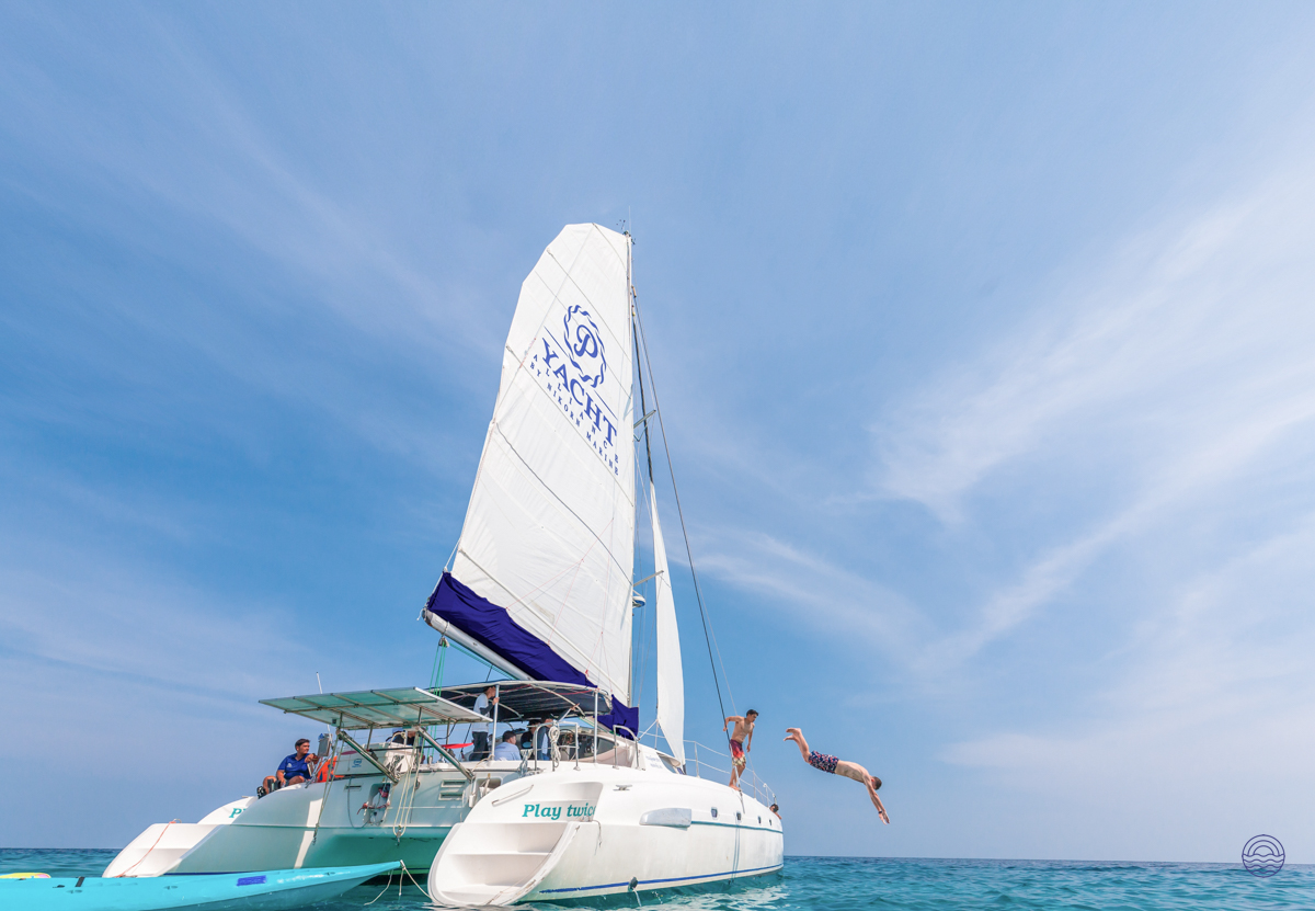 Guests leap from a white catamaran into the inviting blue waters during a cruise near Phuket.