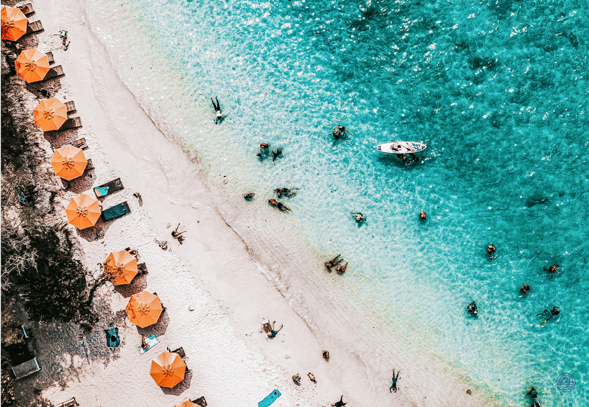 People relaxing and swimming in the clear turquoise waters of a beautiful Phuket beach.
