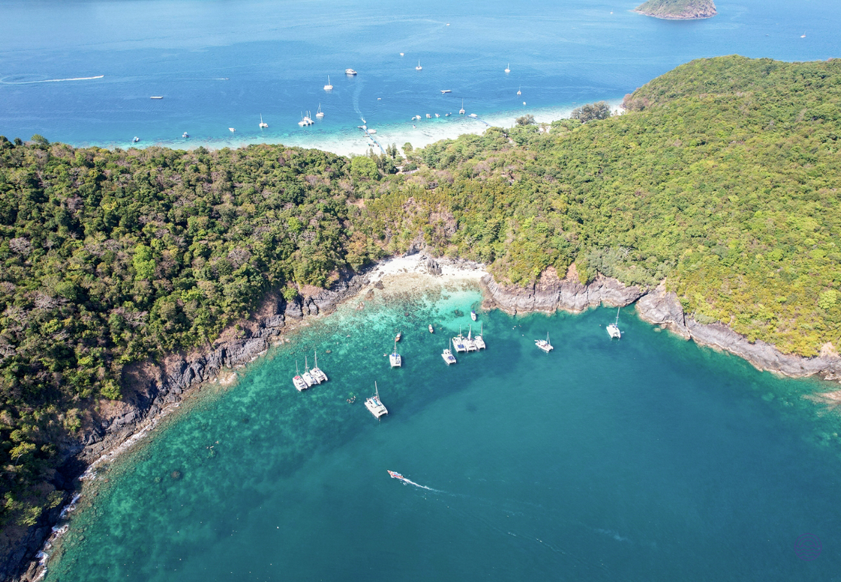 Boats anchored in a beautiful turquoise bay surrounded by lush green islands near Phuket.