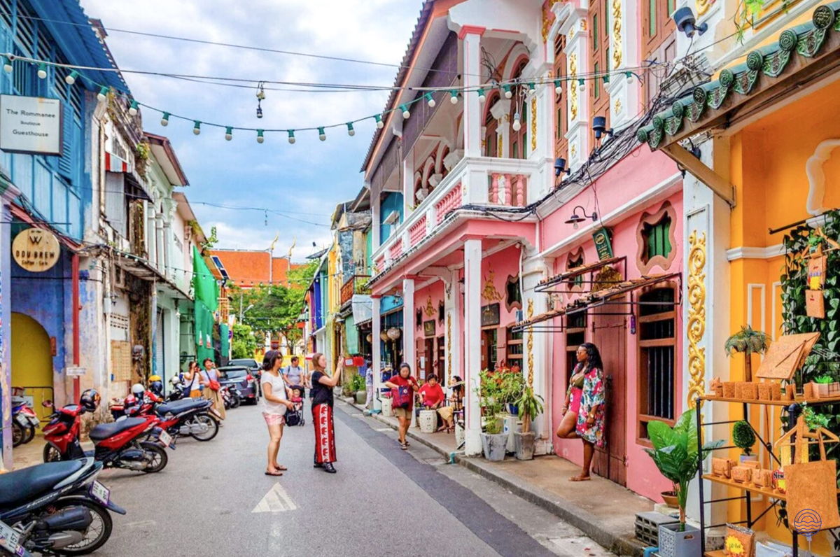 People stroll along a vibrant street lined with colorful historic Sino-Portuguese buildings in Phuket Old Town.