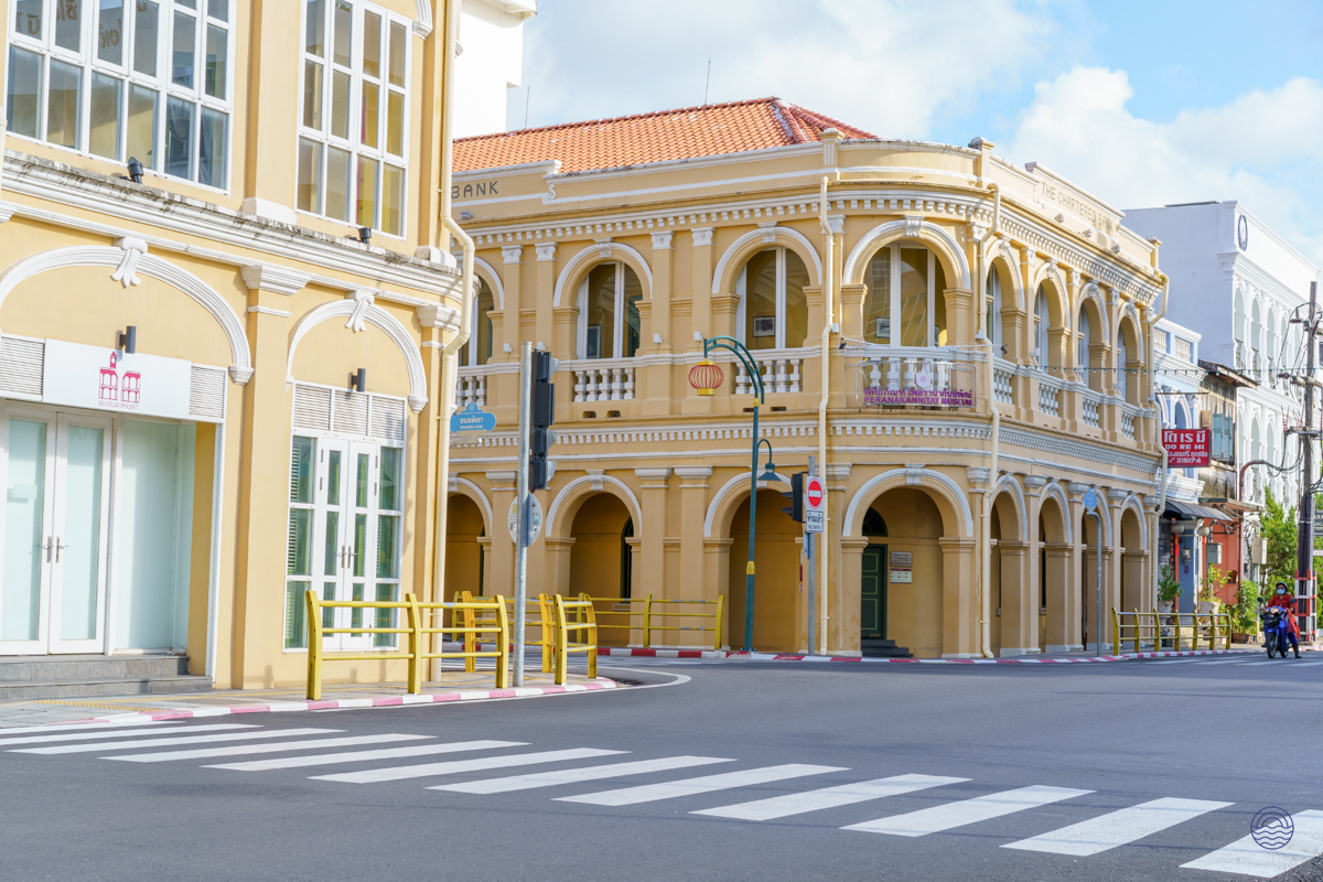 Charming yellow colonial buildings with arched windows line a quiet street in Phuket Old Town.