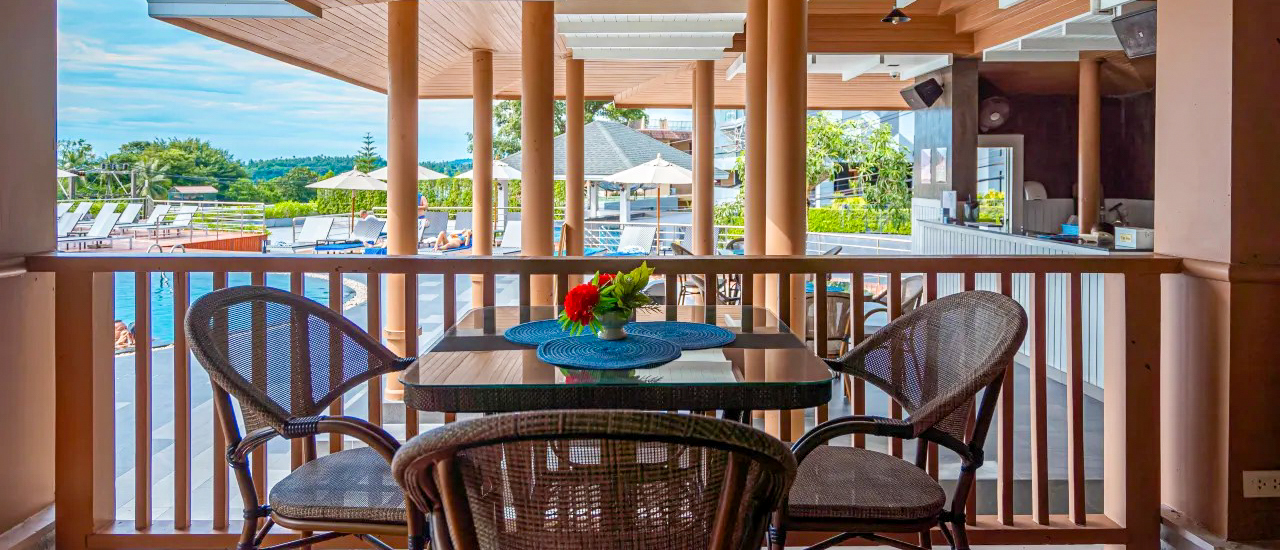 An inviting resort balcony in Phuket overlooking a swimming pool and lush tropical greenery.