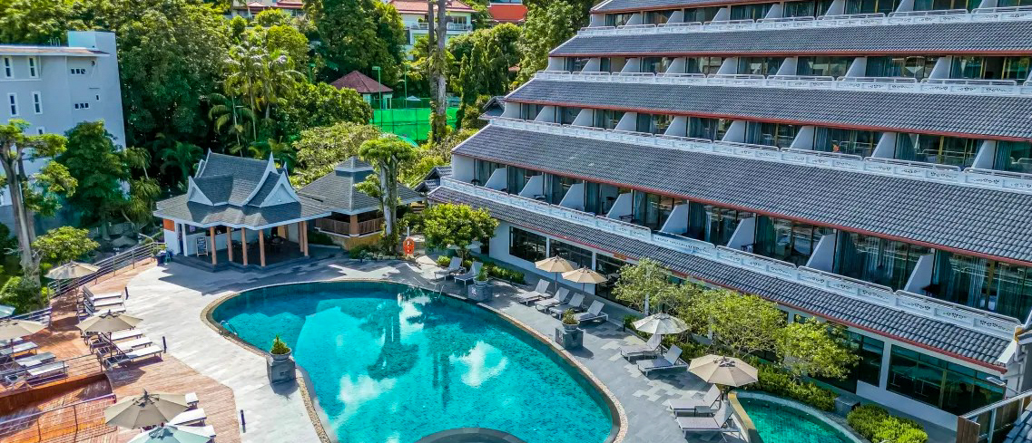 Aerial view of a serene resort in Phuket featuring a large swimming pool and traditional Thai pavilion.