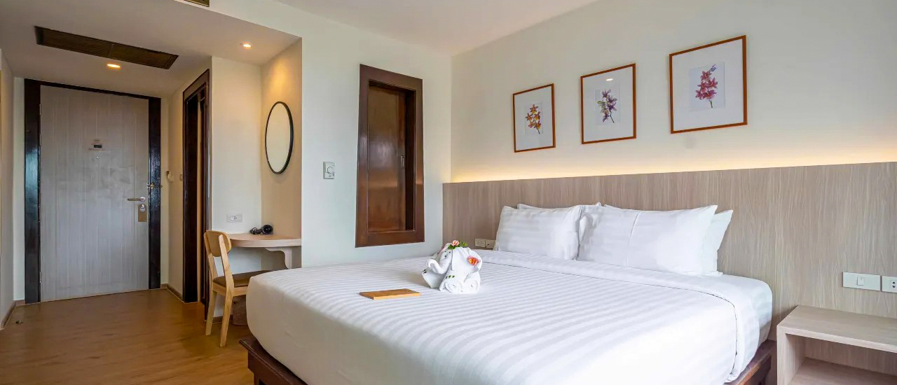 A clean and inviting hotel room with a large bed, white linens, and modern decor.