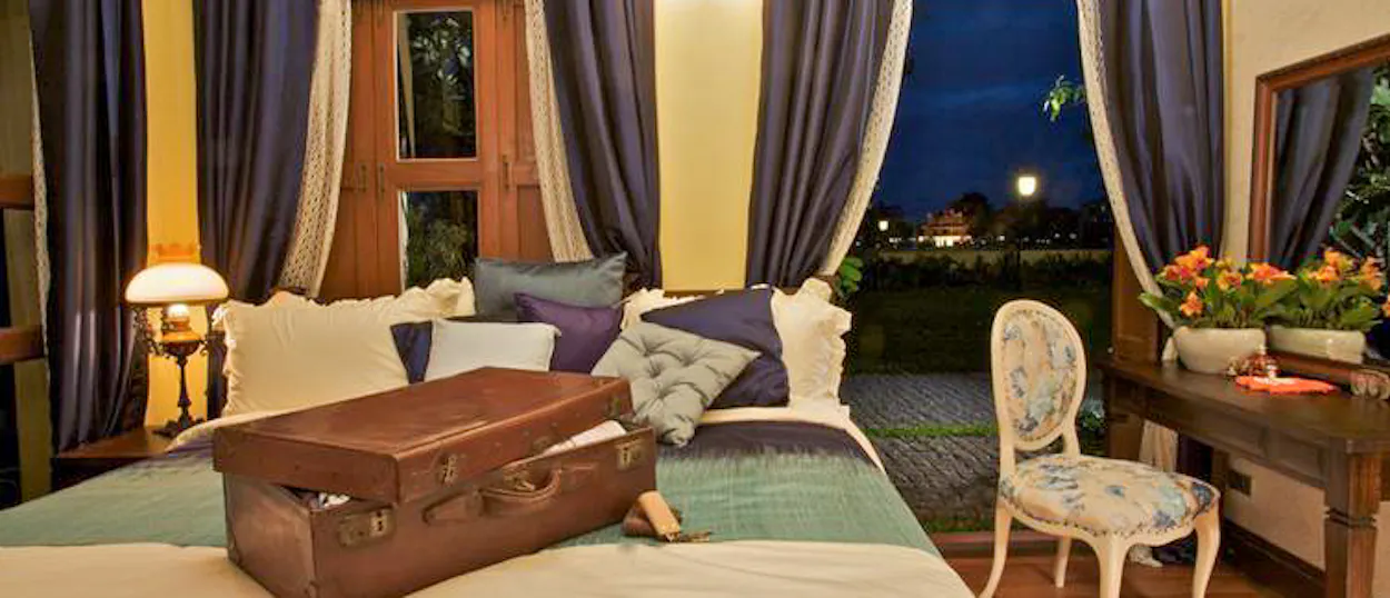 A cozy hotel room in Bangkok at night with an open suitcase on the bed, ready for guests.