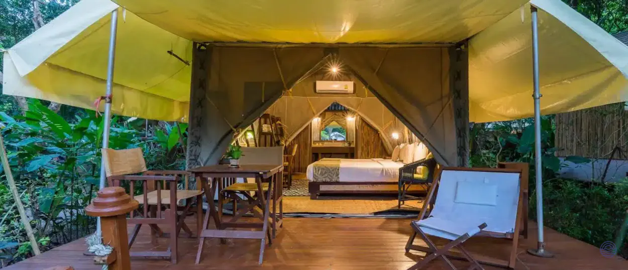 Luxurious glamping tent with a comfortable bed and outdoor deck in the lush Kanchanaburi jungle.