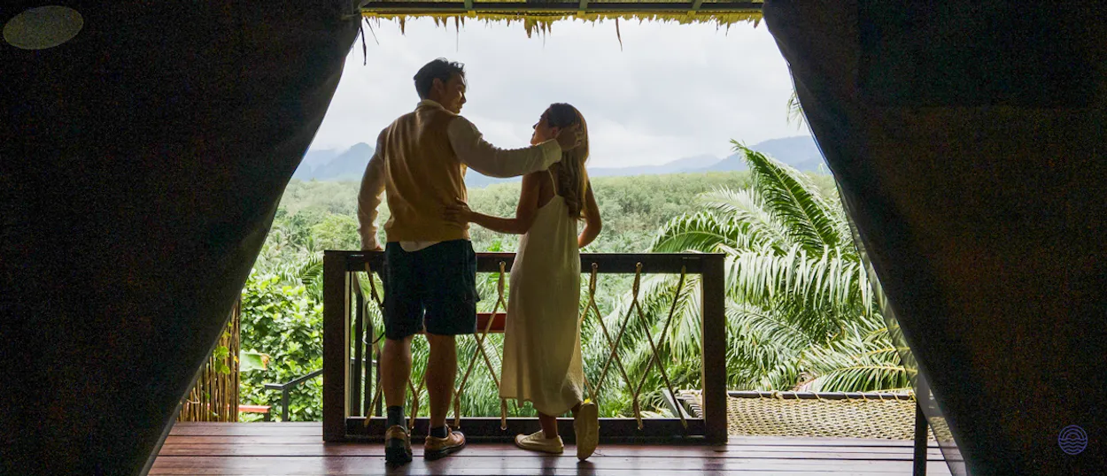 A couple embraces on a balcony overlooking the lush rainforests of Khao Sok National Park.
