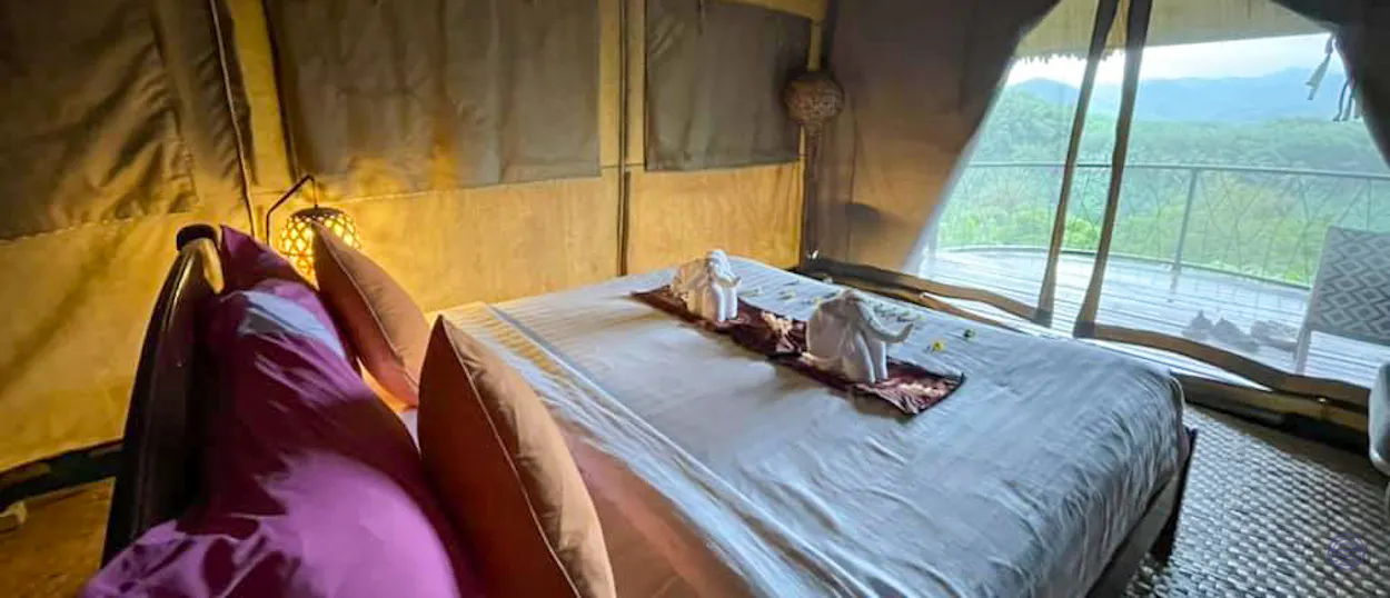 Inviting glamping tent in Khao Sok featuring a comfortable bed, elephant towels, and a jungle view.