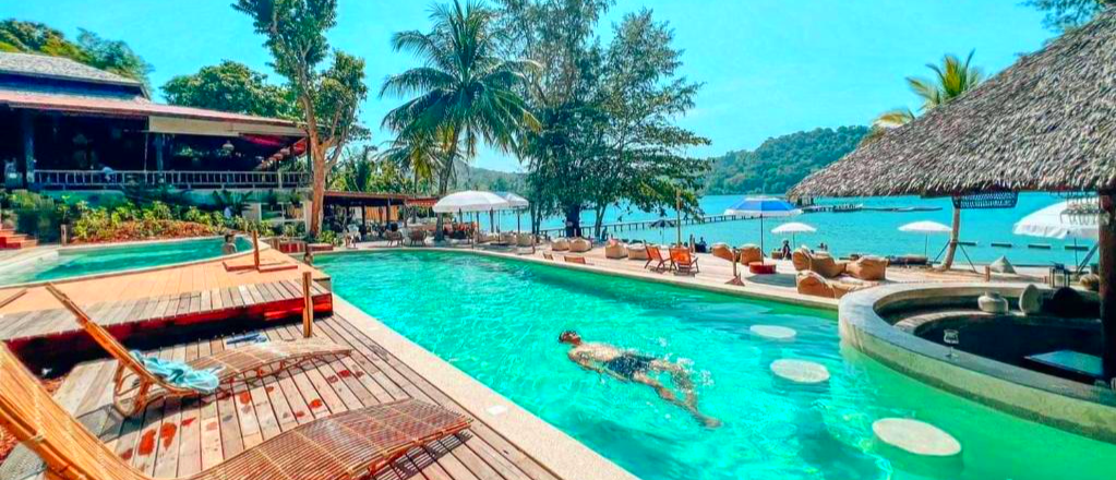 Man swimming in a beautiful resort pool with a swim-up bar and ocean view on Koh Kood.