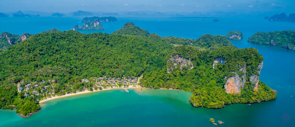 Serene Koh Yao Noi island with a long sandy beach, turquoise sea, and a tropical resort.