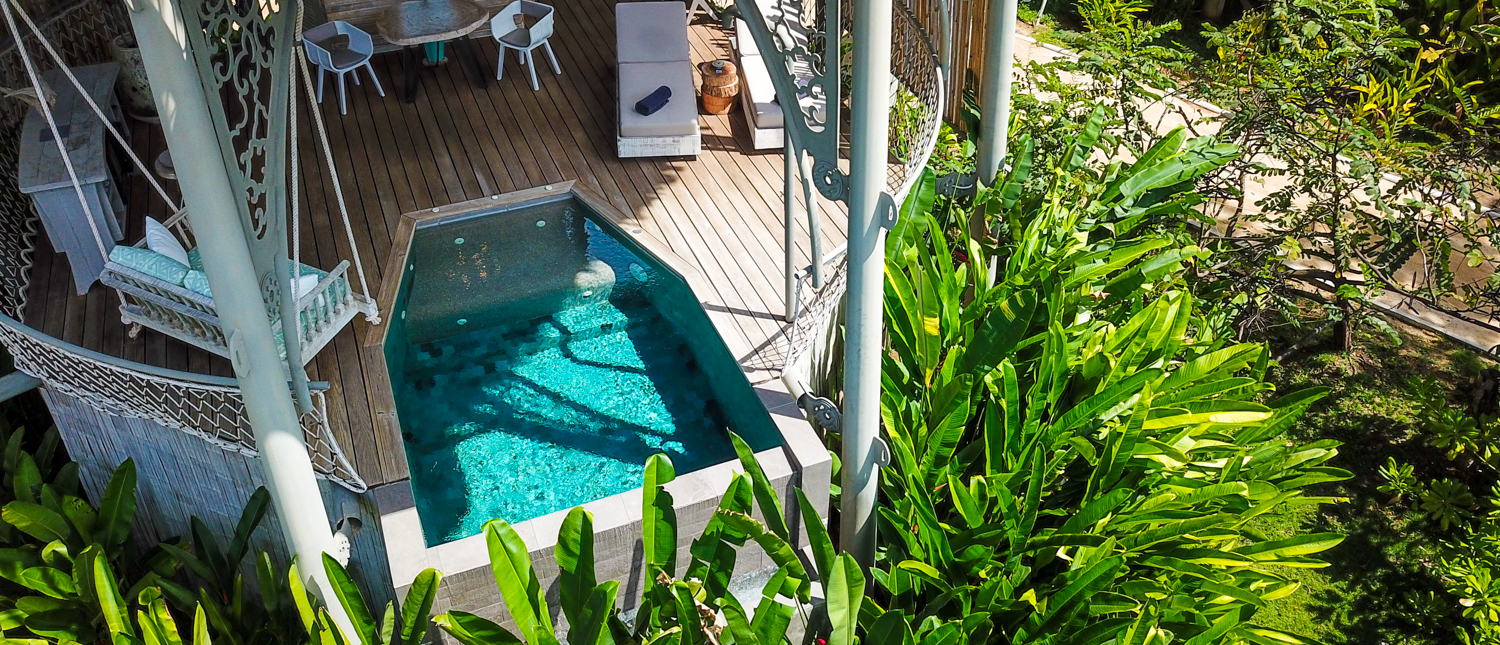 A luxurious treehouse deck with a plunge pool and white furniture surrounded by lush greenery on Koh Yao Noi.