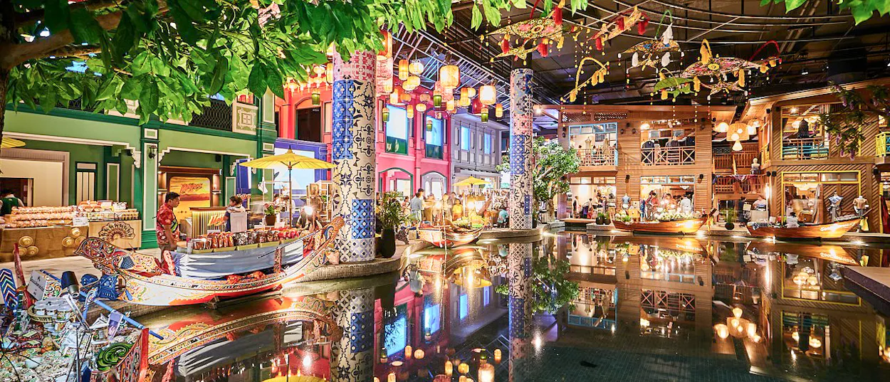 Colorful indoor floating market in Bangkok with traditional boats, shops, and lively atmosphere.