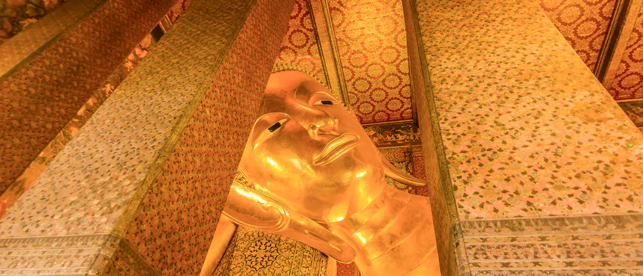 Close-up of the serene golden reclining Buddha statue inside Wat Pho temple, Bangkok.