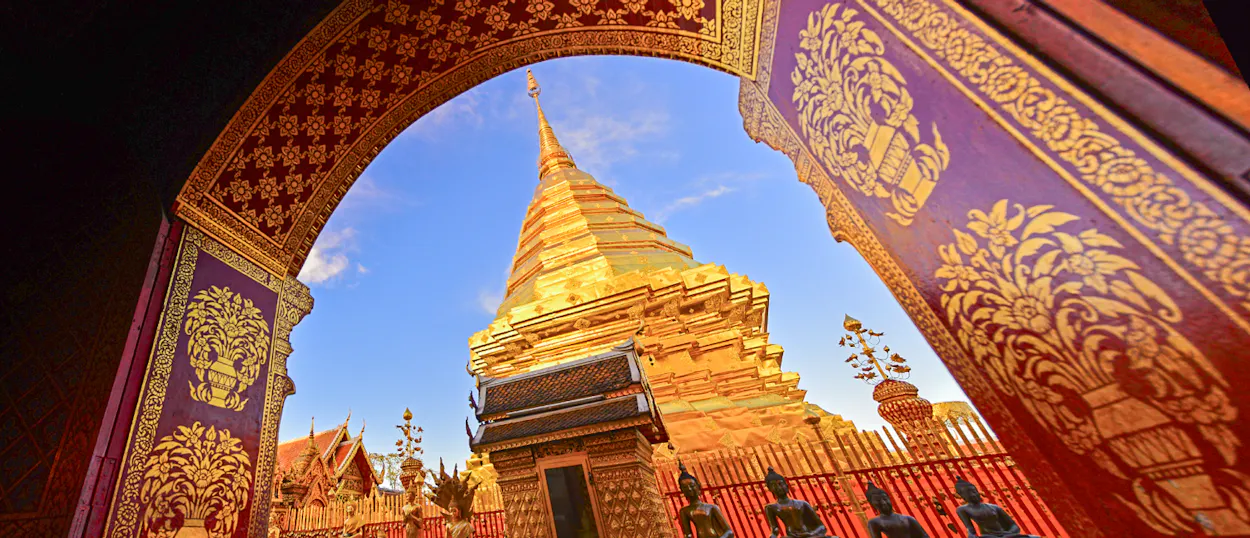 A majestic golden chedi at Wat Phra That Doi Suthep in Chiang Mai, framed by a decorative archway.