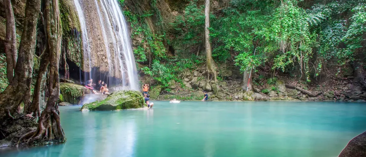 People enjoy swimming in the stunning turquoise pool of Erawan Waterfall in Kanchanaburi, Thailand.