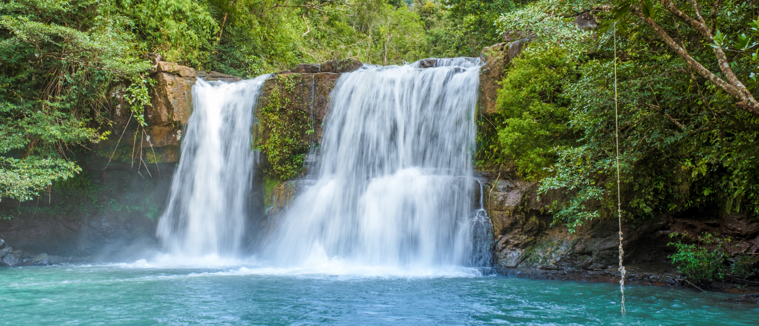 Khlong Chao Waterfall on Koh Kood with lush jungle and a rope swing over a blue pool.
