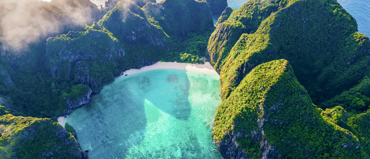 Aerial view of Koh Phi Phi's Maya Bay, featuring lush green cliffs and stunning turquoise water.