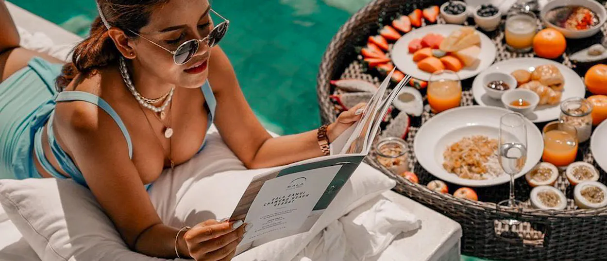 Woman enjoying a luxurious floating breakfast in a private pool in Koh Samui, Thailand.