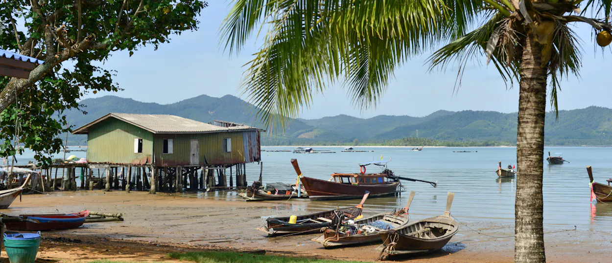 Traditional longtail boats and a stilt house on the shore of a fishing village at Koh Yao Noi.