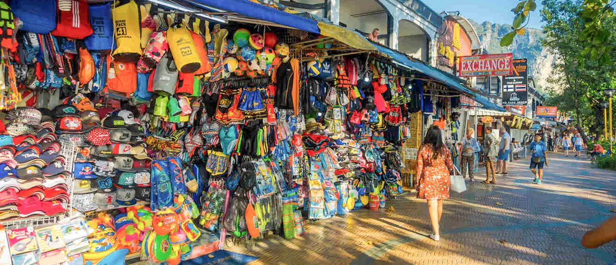 A vibrant street market in Krabi with colorful stalls and people browsing souvenirs.