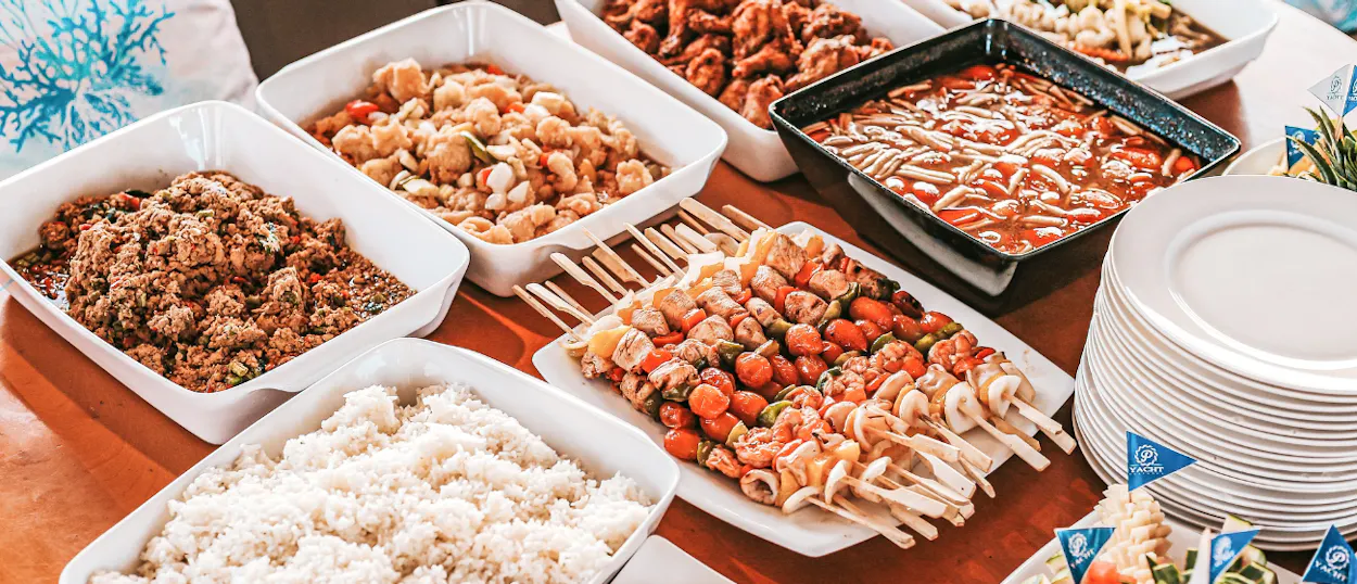 A sumptuous Thai buffet dinner with rice, curries, and seafood skewers served on a Phuket sunset cruise.
