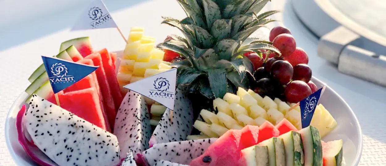A refreshing plate of tropical fruits with watermelon, pineapple, and dragon fruit on a Phuket yacht.
