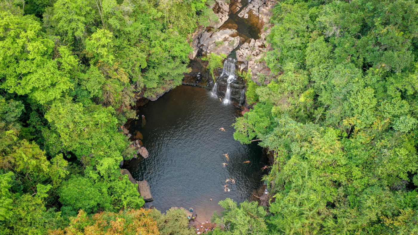 Aerial view of Khlong Chao Waterfall on Koh Kood, with people swimming in the jungle pool.