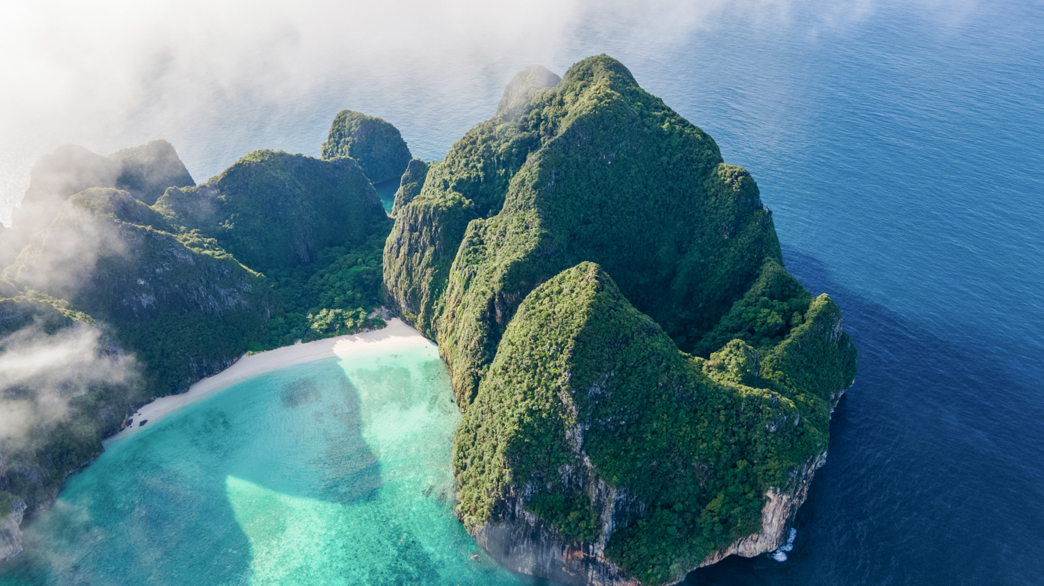 Dramatic green limestone cliffs, a white sand beach, and turquoise sea at Koh Phi Phi.